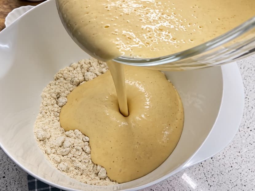 Shtimi i përzierjes së vezëve te mielli me arra për përgatitjen e brumit të tatliut.